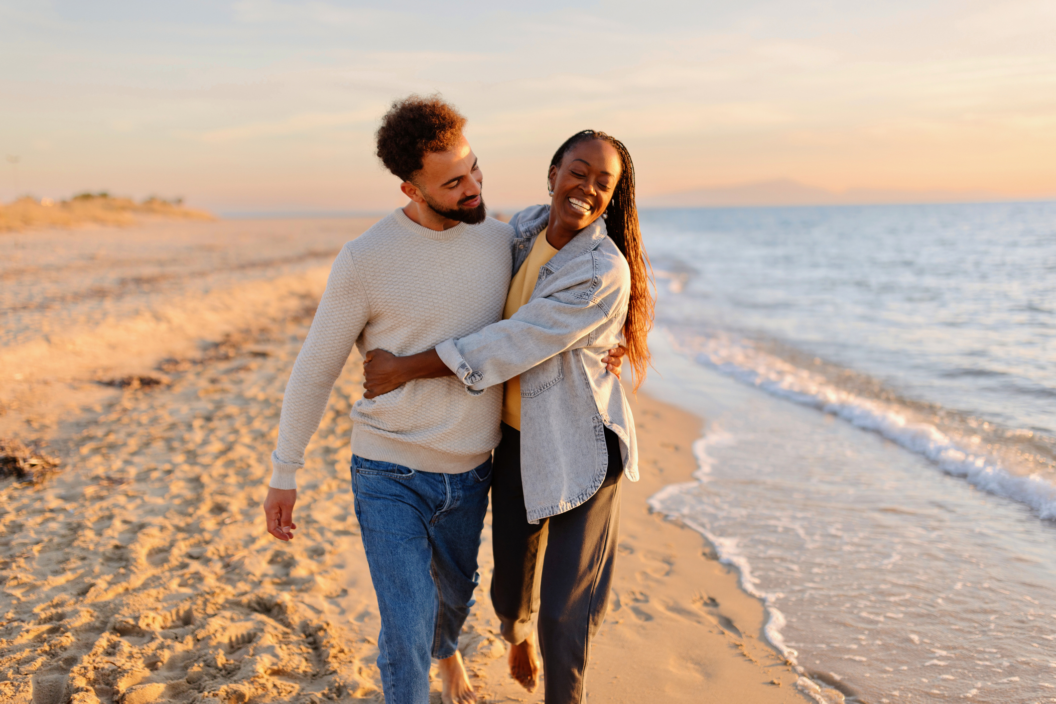 Couple walking at beach during sunset Couple walking at beach during sunset